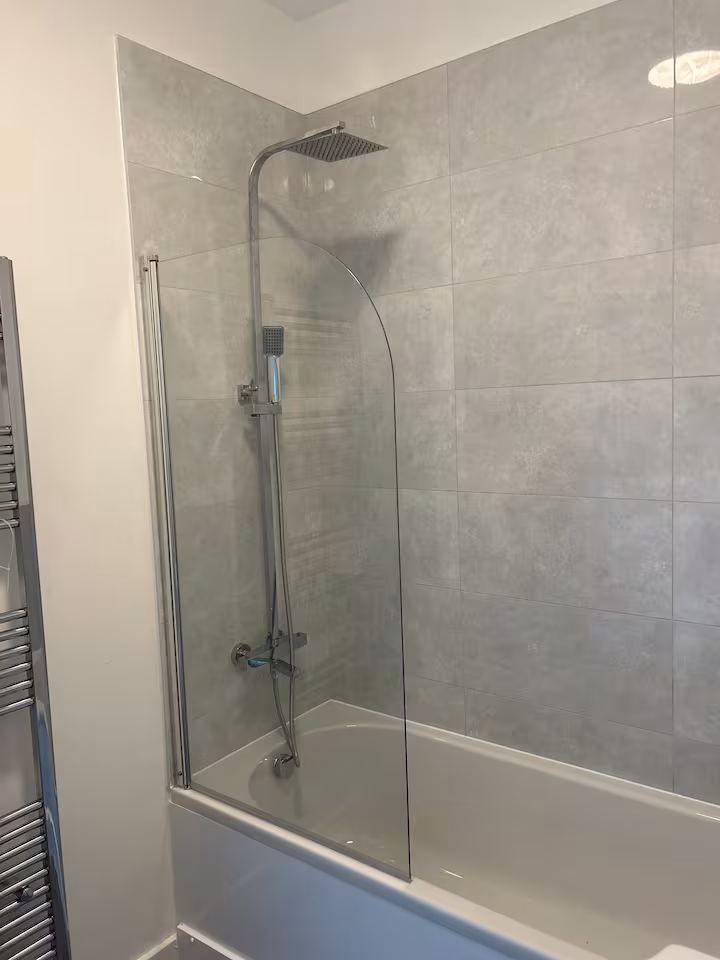 Shower and bathtub located in a bright, modern bathroom with silver multi-tier towel rail