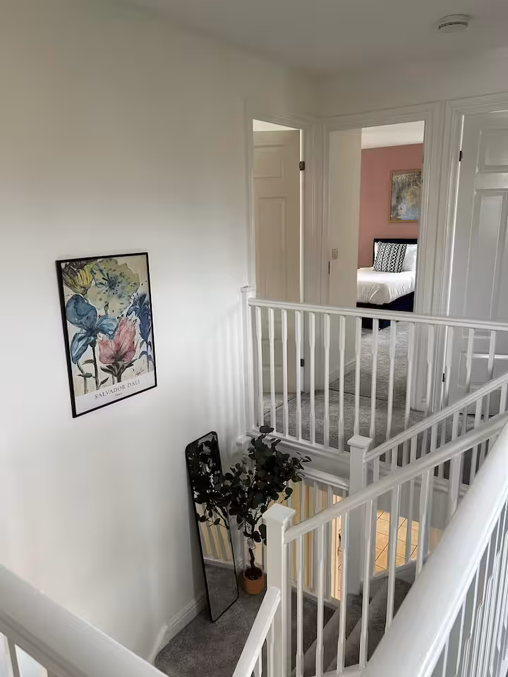 Stairs with fluffy grey carpet, surrounded by white bannister and decorations