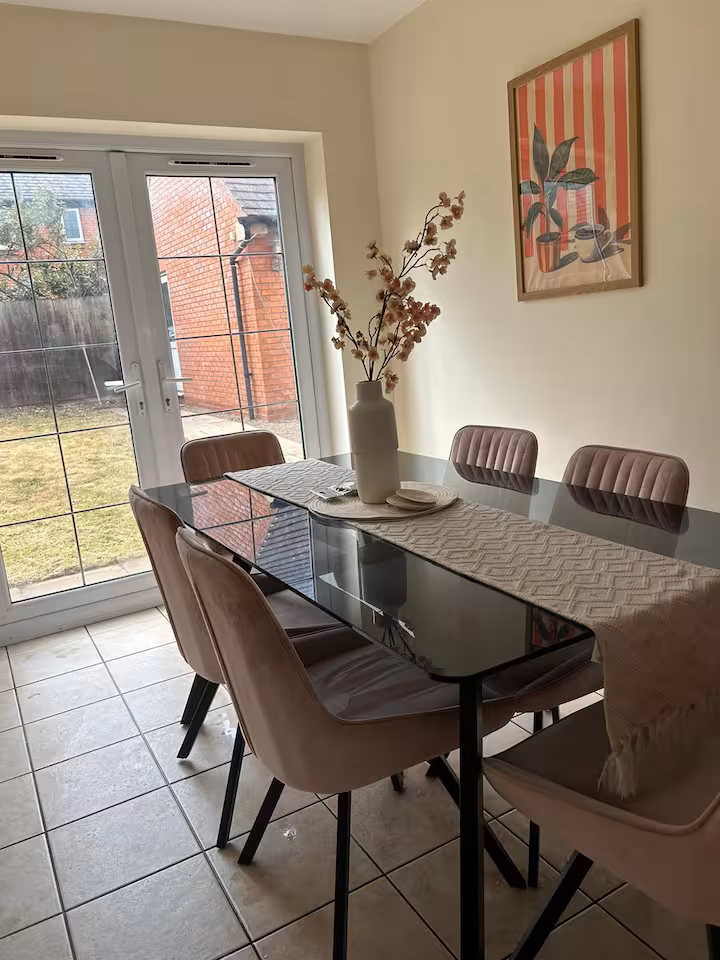 Large glass dining table and chairs located in an airy dining room with direct access to garden