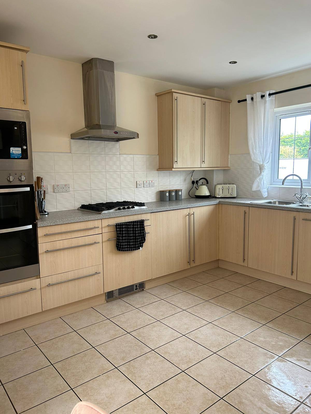 Retro style kitchen including square floor tiles, oven, extractor fan, stove, kettle, toaster, and sink